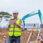 Construction engineer wear safety uniform under inspection and survey workplace by tablet with excav